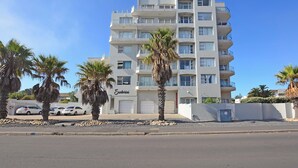 A multi-story building with balconies, a name sign, and parked cars. - Mountain and Oceanview at Blouberg (Cape Town)