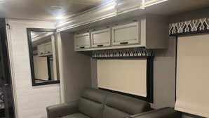 Una cucina camper compatta con lavello integrato, un piccolo spazio ristoro e un’area salotto con divano.