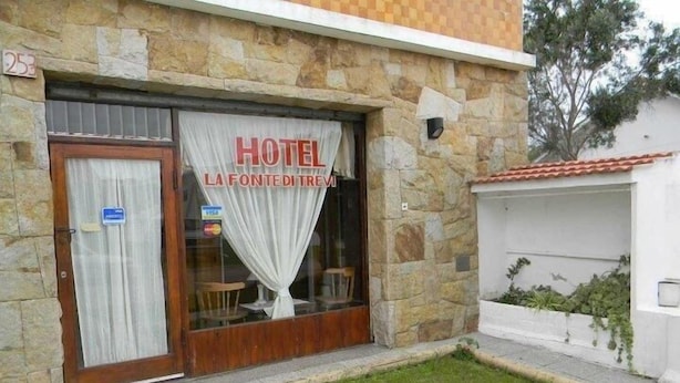 Ein Hotel mit einer Stein-Fassade, einer Holztür und einem Schild, auf dem 'HOTEL LA FONTE DI TREVI' steht.
