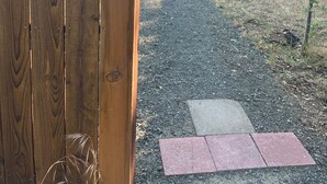 A wooden gate with a 'Well House' sign, a gravel path, and a backyard with a patio area. - The Well House with outdoor seating and loft! (Middletown)