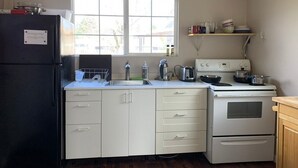 A compact kitchen with a refrigerator, stove, sink, and a window providing natural light. - The Well House with outdoor seating and loft! (Middletown)