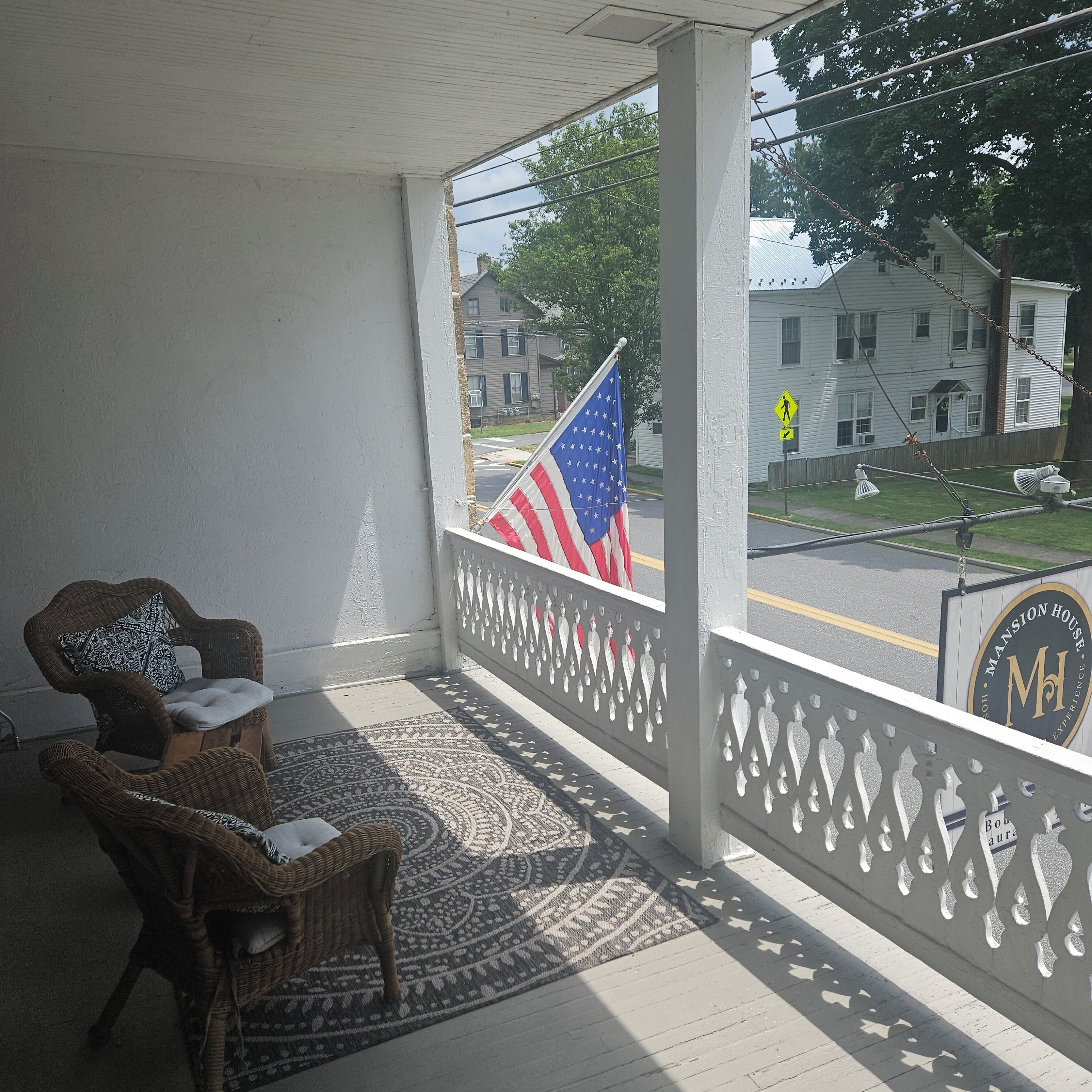 A porch with wicker furniture and a patterned rug.