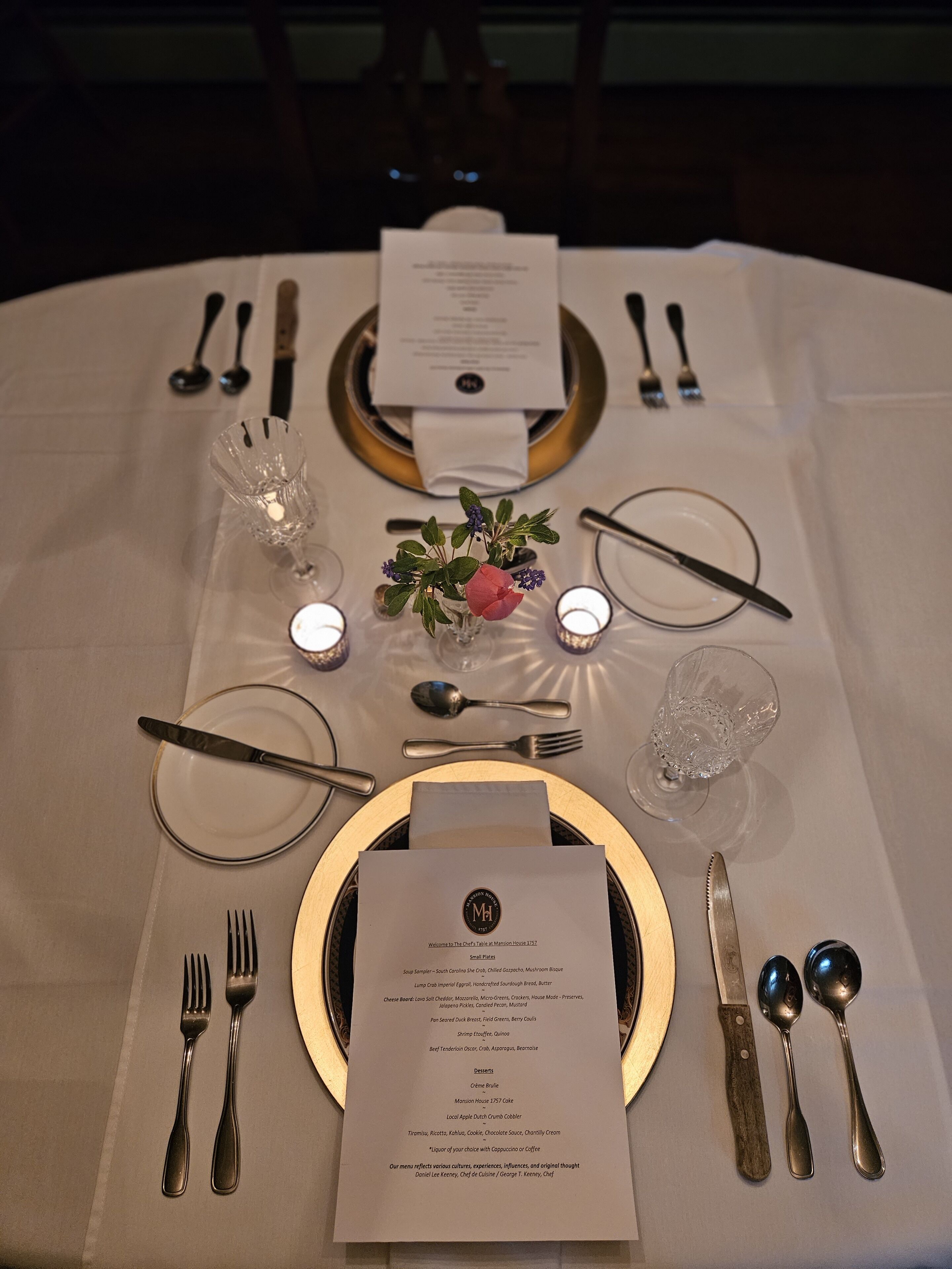 Une table à manger dressée de façon élégante, avec un menu, des couverts et des bougies.