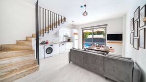 Eine moderne Küche mit integriertem Waschmaschine, einem grauen Sofa und einer Treppe mit Holzbodenstufen.