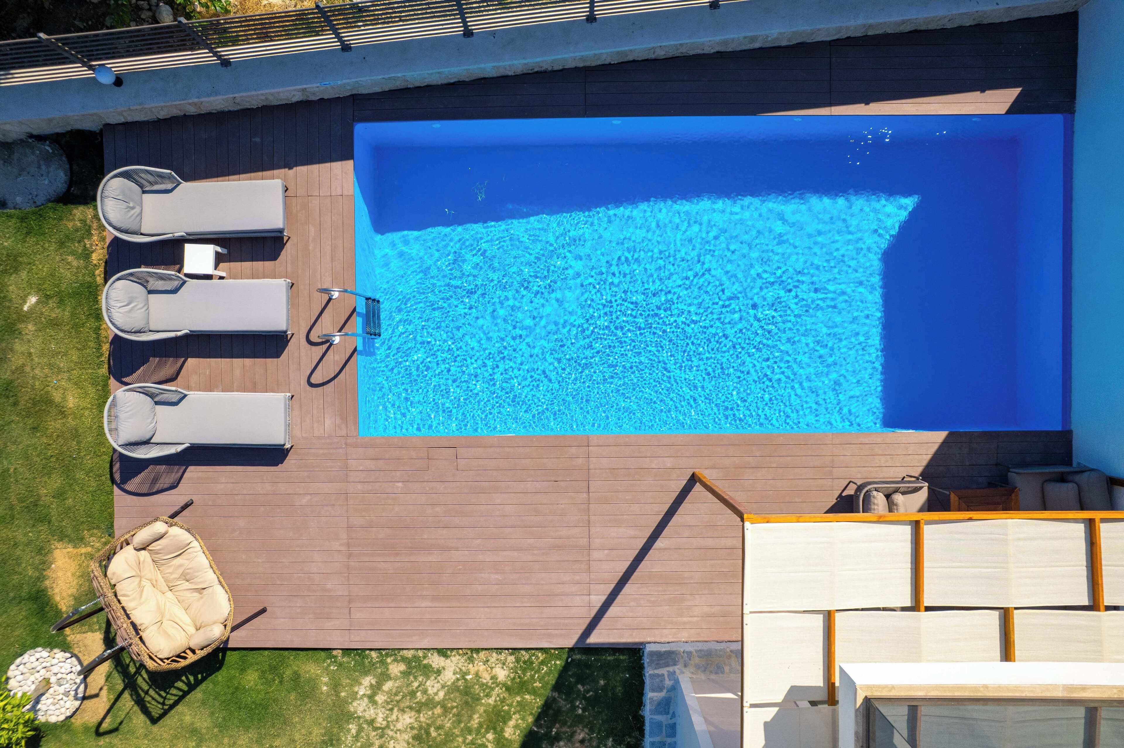 An aerial view of a swimming pool with lounge chairs and a small table.