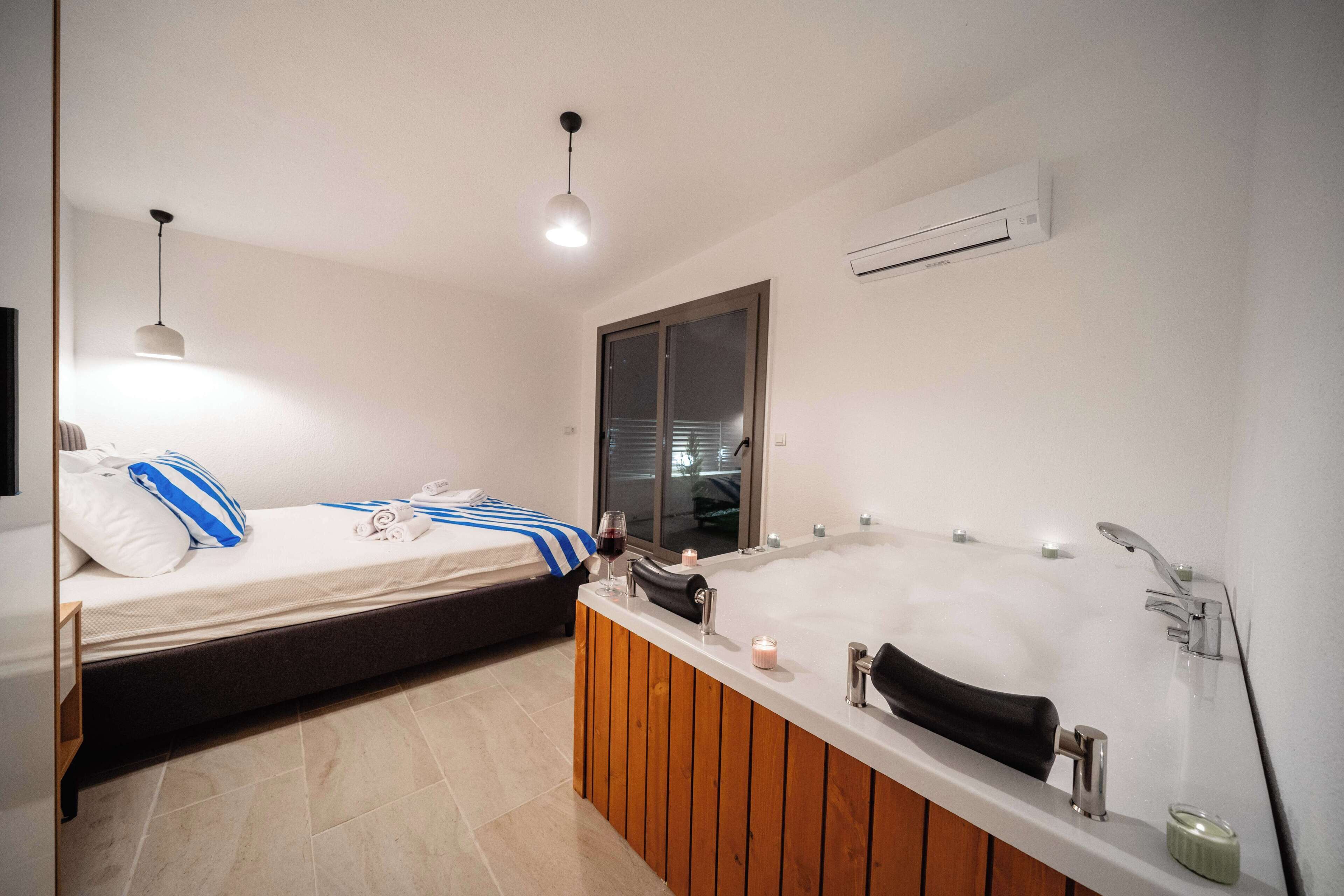 Uma casa de banho moderna com uma banheira grande, chuveiro e área de cama separada.