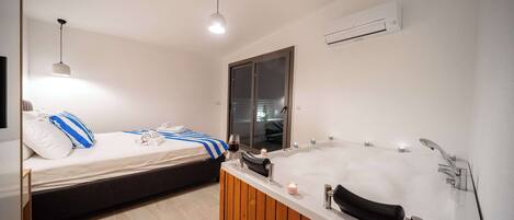 Uma casa de banho moderna com uma banheira grande, chuveiro e área de cama separada.
