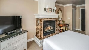 Ein Hotelzimmer mit Fernseher, Kamin, Bett und Schreibtisch mit Stuhl.