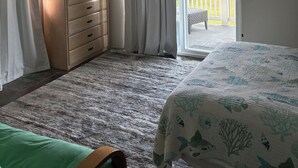 A bedroom with a bed, a dresser, a ceiling fan, and a sliding glass door leading to a balcony. - Cozy studio in awesome Kaaawa with WiFi, AC, fitness room (Kaaawa)