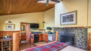 Una habitación acogedora con cama, chimenea, zona de cocina y mesa de comedor.