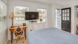 Un dormitorio con una cama, un escritorio con lámpara, una televisión y una puerta.
