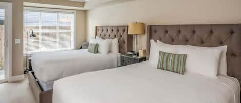 Een hotelkamer met twee bedden, een nachtkastje, een lamp en een raam met zonwering.