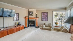 A bedroom with a large bed, a fireplace, a television, and a sofa.