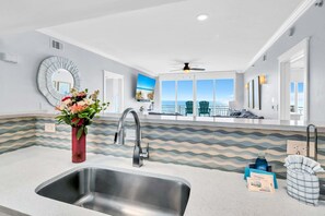 Una cucina moderna con un lavello capiente, uno specchio decorativo e vista sull'oceano grazie a ampie finestre.