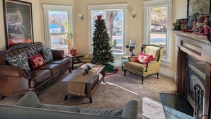 A cozy living room with a brown leather sofa, a patterned armchair, a wooden coffee table, and a Christmas tree. - Spacious Victorian-Style Family Retreat | 5 Ensuite Bedrooms + Event-Ready Yard (Kanab)