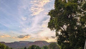 A balcony with a metal table and chair, overlooking a residential area with houses and a hilly landscape. - Spacious Victorian-Style Family Retreat | 5 Ensuite Bedrooms + Event-Ready Yard (Kanab)