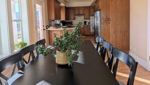 A dining area with a long table, chairs, and a potted plant. - Spacious Victorian-Style Family Retreat | 5 Ensuite Bedrooms + Event-Ready Yard (Kanab)
