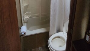 A small bathroom with a toilet, a shower stall, and a curtain. - Unique getaway or travel stop, just 10 minutes off TransCan Highway (Grand Sudbury)