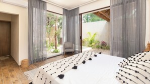 A bedroom with a large bed, a ceiling fan, and a view of a garden through the window. - ZENDA TULUM LUXURY VILLAS (Tulum)