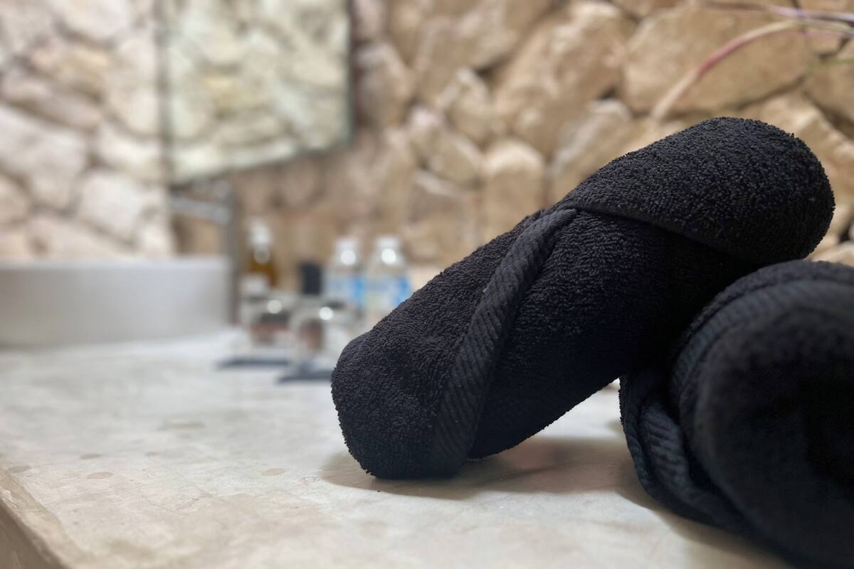 A bathroom with a stone wall, a sink, and a towel on the counter.