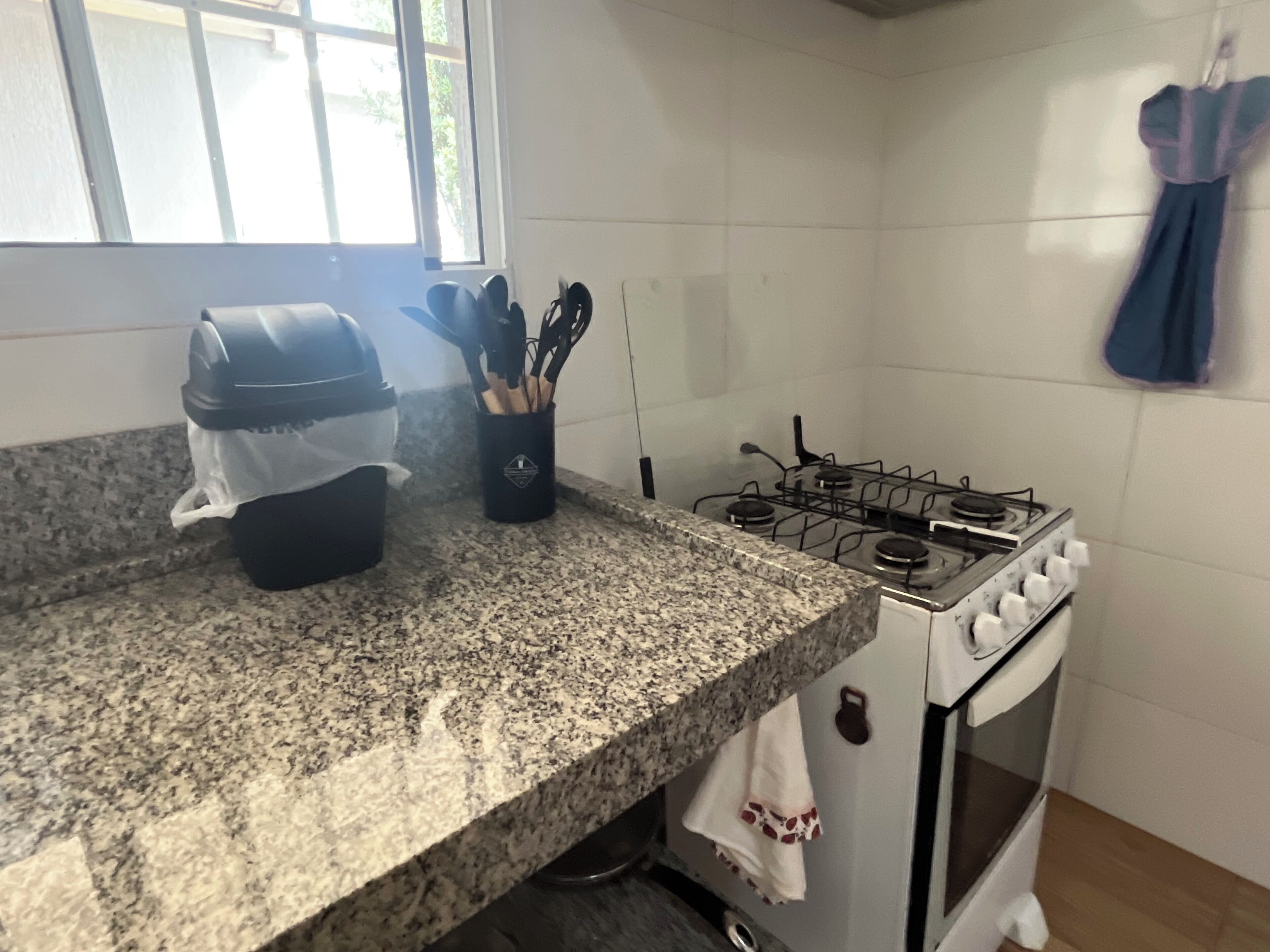 Een keuken met granieten aanrecht, een gasfornuis en een witte oven.