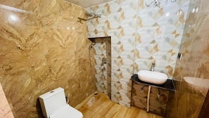 A bathroom with a marble floor, a white toilet, a sink with a mirror, and a shower area. - Sri Madhubani Enclave (Prayagraj)