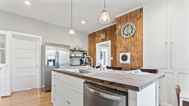 Una cucina moderna con parete decorata in legno, elettrodomestici in acciaio inossidabile e illuminazione a sospensione.