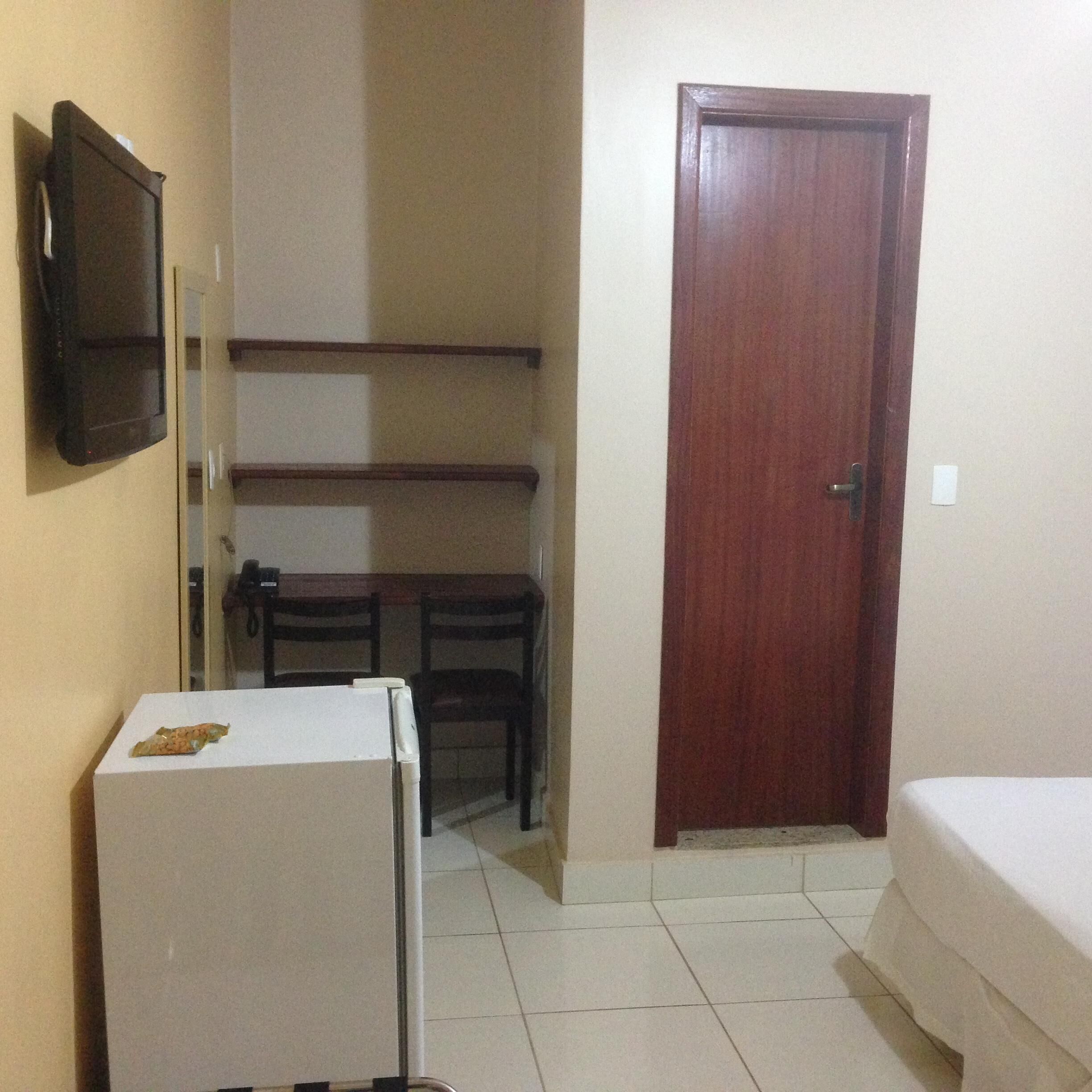 A small, compact room with a white refrigerator, a wooden door, and a small table with chairs.