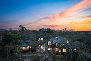 A secluded resort with multiple treehouses connected by walkways, surrounded by dense foliage.