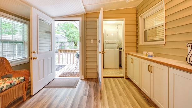 A kitchen with wooden cabinets, a countertop, and a door leading to a laundry area. - Fish, Relax & Repeat: Home w/ Yard in Eastpoint! (Eastpoint)
