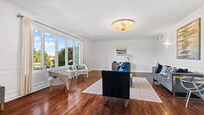 A spacious living room with hardwood flooring, a chandelier, a sofa, a coffee table, and a dining area with a chair and table. - Charming 4-bedroom house with WiFi, AC in upscale Oak Brook,near Oak brook mall (Oak Brook)