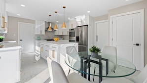 A modern kitchen with white cabinetry, stainless steel appliances, and a glass dining table. - Charming 4-bedroom house with WiFi, AC in upscale Oak Brook,near Oak brook mall (Oak Brook)