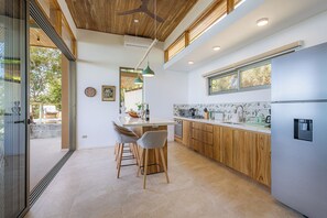 Eine moderne Küche mit Holzschränken, einem Edelstahlkühlschrank und einer Bar mit Sitzgelegenheiten.
