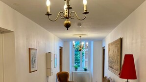 A hallway with a chandelier, two chairs, a red floor lamp, and a radiator. - Charming 4-bedroom townhome in Rabastens-de-Bigorre at the base of the Pyrenees. (Rabastens-de-Bigorre)