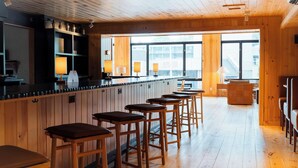Ein Holzinterieur mit Barbereich, Hockern und Blick durch große Fenster.