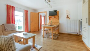 A cozy living room with a sofa, a coffee table, and a dining area with a table and chairs. There's a TV mounted on the wall and a wooden cabinet with drawers. - Ferienwohnung Schöder (Schöder)