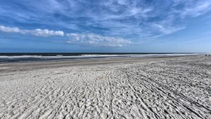 A wide sandy beach with visible tire tracks and a clear view of the ocean under a partly cloudy sky. - Private Beach Access: Hilton Head Island Condo! (Hilton Head Island)