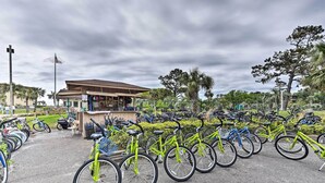 A bicycle parking area with multiple bicycles, a small kiosk, and a building with a sloped roof. - Private Beach Access: Hilton Head Island Condo! (Hilton Head Island)