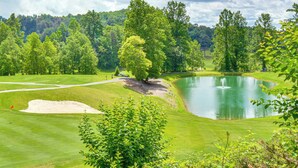 A golf course with a pond, surrounded by lush greenery and trees. - Hike, Golf & Swim: Blue Ridge Cabin Escape (Clayton)