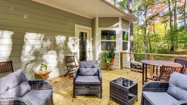 A covered outdoor deck with wicker furniture, a small table, and a potted plant. - Hike, Golf & Swim: Blue Ridge Cabin Escape (Clayton)