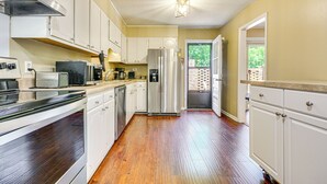 Una cocina con gabinetes blancos, electrodomésticos de acero inoxidable y piso de madera.