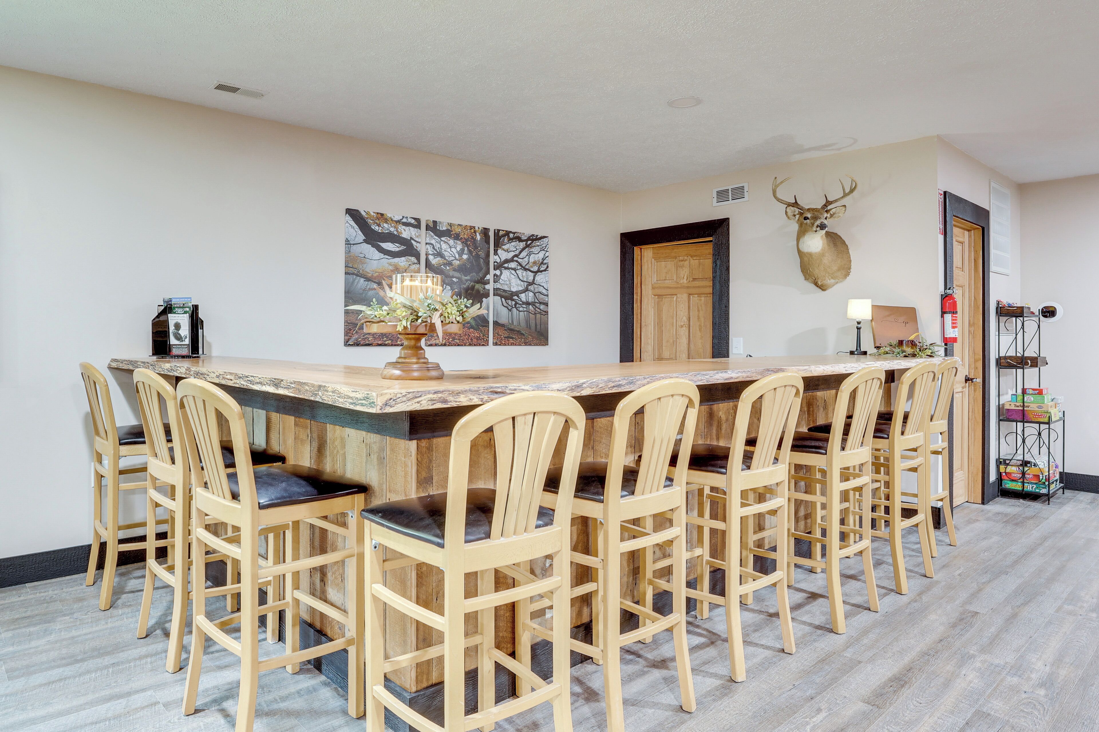 Un coin repas avec une table et des chaises en bois, une tête de cerf accrochée au mur et un tableau.
