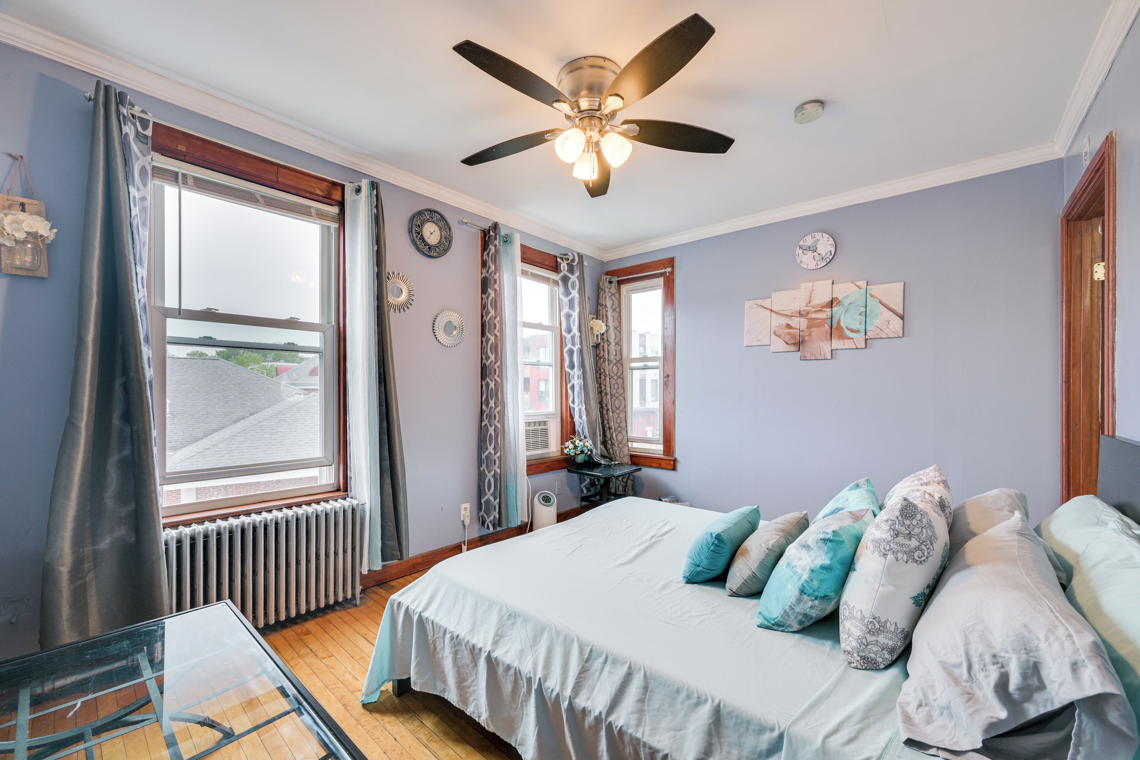 A bedroom with a bed, a ceiling fan, a window, and a radiator.