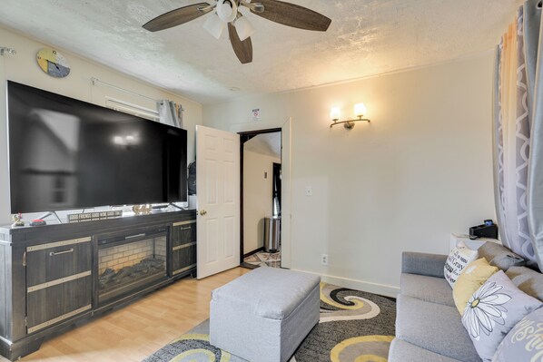 A living room with a flat-screen TV, a fireplace, a ceiling fan, and a sofa with decorative pillows. - 6 Mi to Boston Common: Apt in Medford! (Medford)