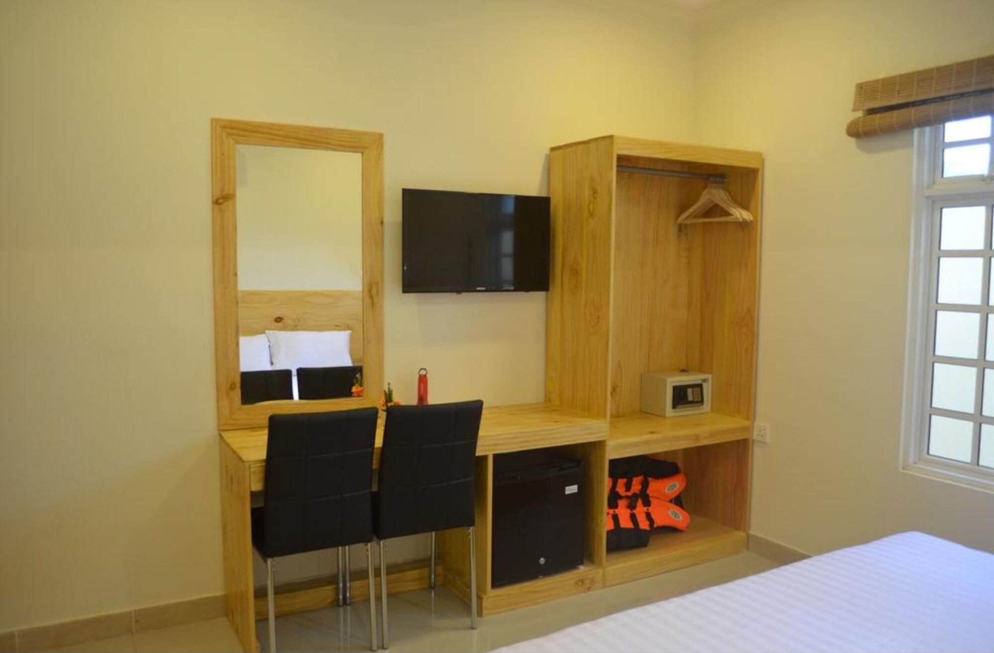 Un dormitorio con un escritorio de madera, una silla, un televisor, un armario y una cama.