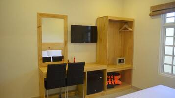 Un dormitorio con un escritorio de madera, una silla, un televisor, un armario y una cama.