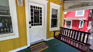 A porch with a white door, a bench, and a colorful doormat. - Charming 2-BRM Cottage in Tranquil Island Heights - Steps from the River (Island Heights)