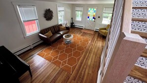 A living room with a brown leather sofa, a round coffee table, and a hexagonal rug. - Charming 2-BRM Cottage in Tranquil Island Heights - Steps from the River (Island Heights)