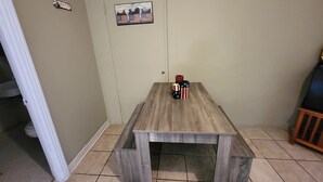 A dining table with a bench, a door with a small picture, and a tiled floor. - The Americana Suite (Buchanan Dam)
