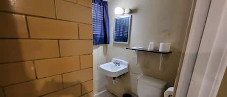 Een kleine badkamer met een wit wastafel, toilet en een blauw gordijn.